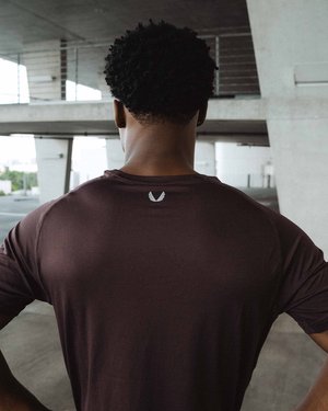Black male fitness model posing for ASRV in front of a concrete wall