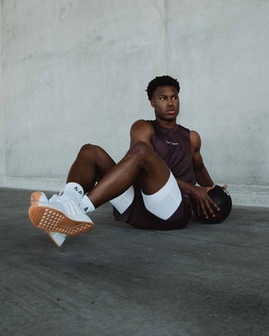 Black male fitness model posing for ASRV in front of a concrete wall
