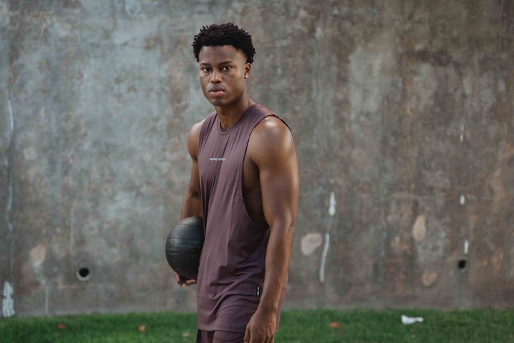 Black male fitness model posing for ASRV in front of a concrete wall