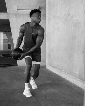 Black male fitness model working out against concrete wall