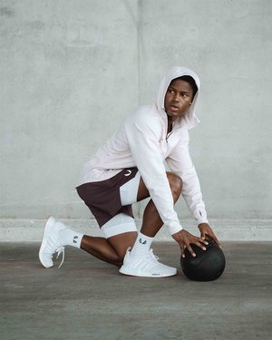 Black male fitness model posing in front of blank concrete wall