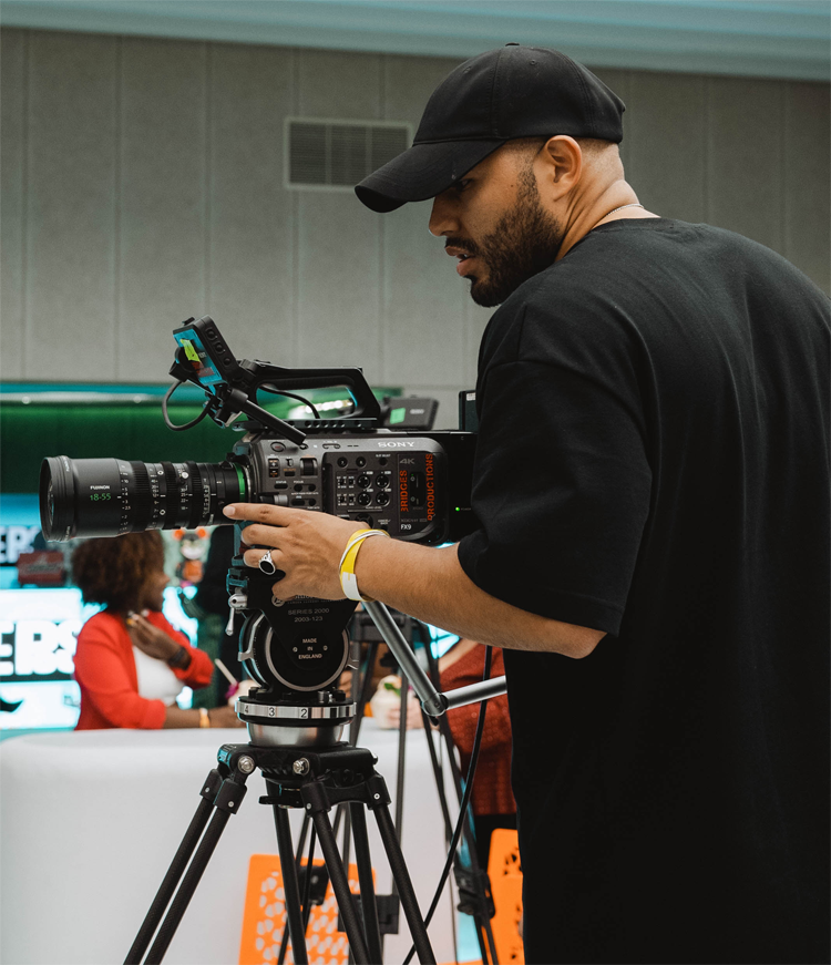 Latino man with Sony FX9 filming a live podcast in a crowd.