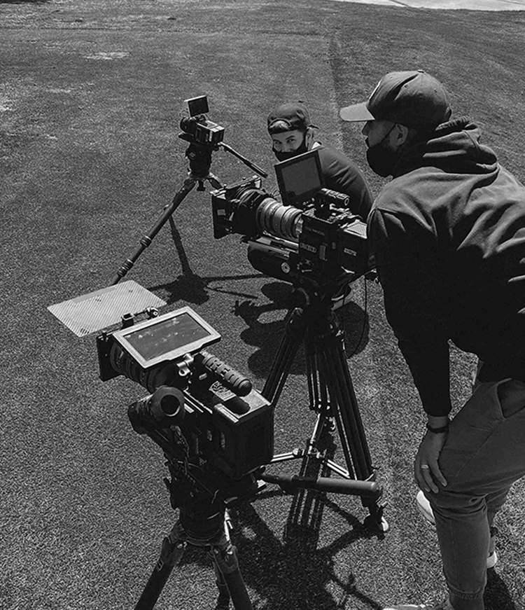 Black and white photo of pre-production with a Red camera filming on a golf course