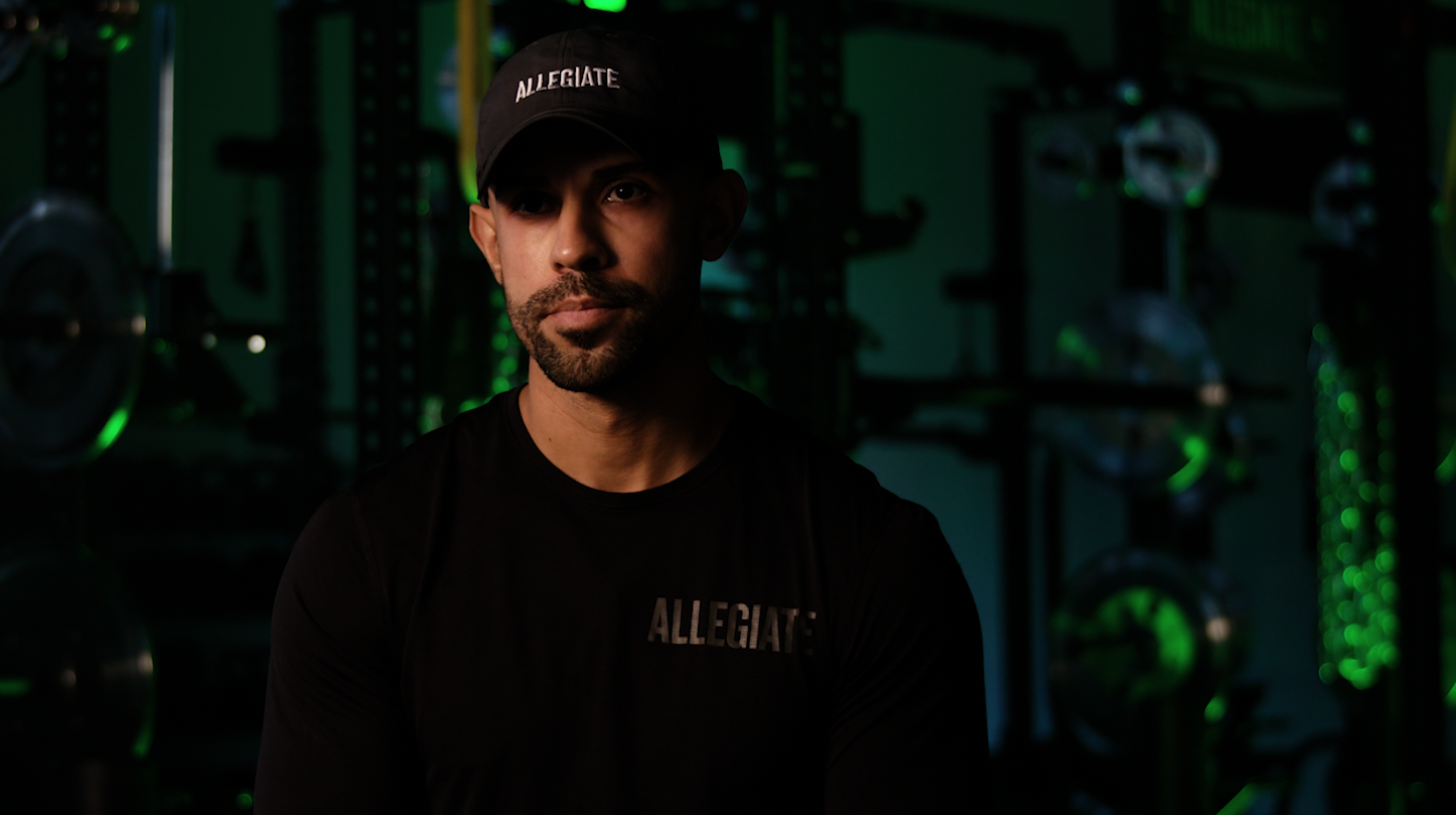 Latino man standing in front of a green light for Allegiate gym interview production lighting.