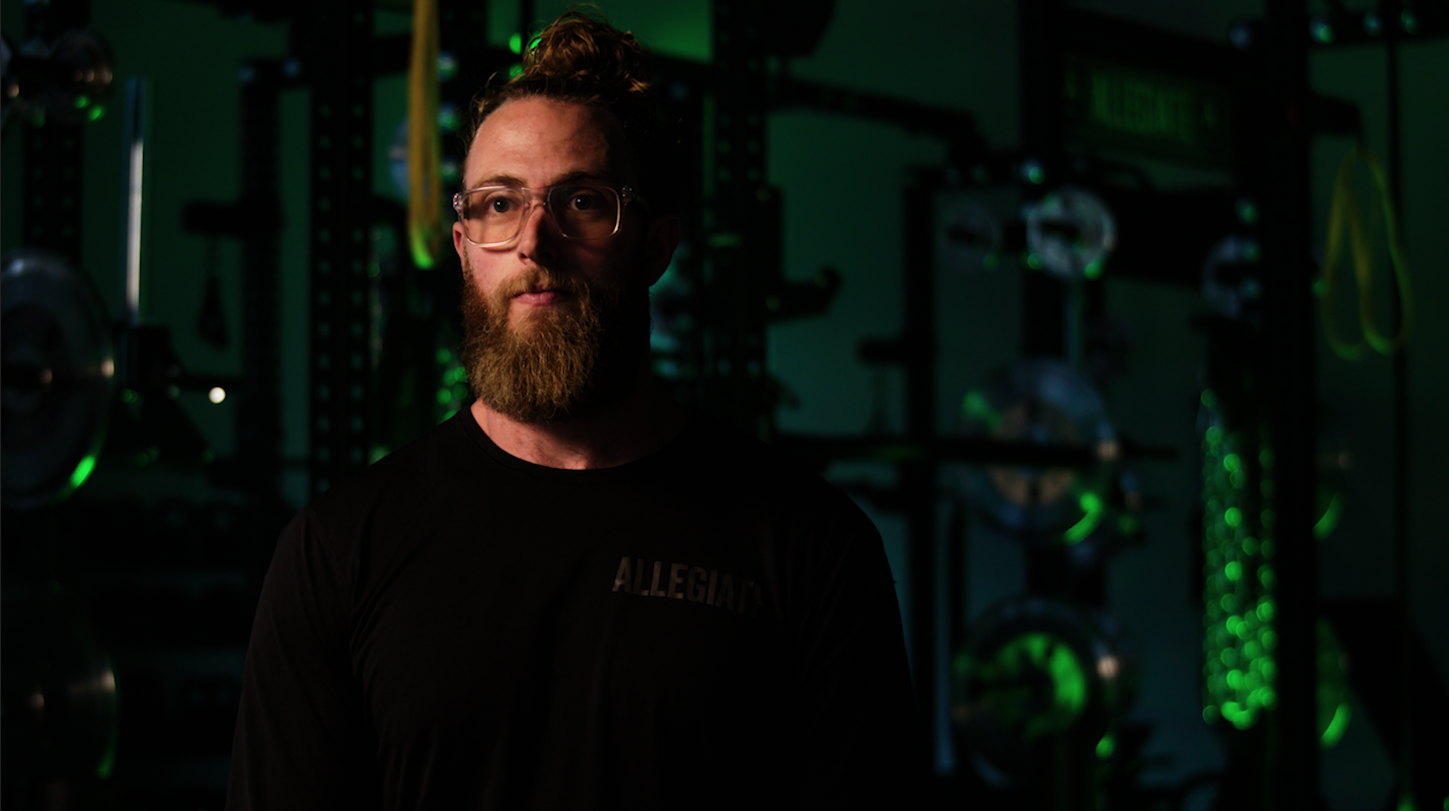 Bearded man standing in front of a green light for a gym interview production lighting.