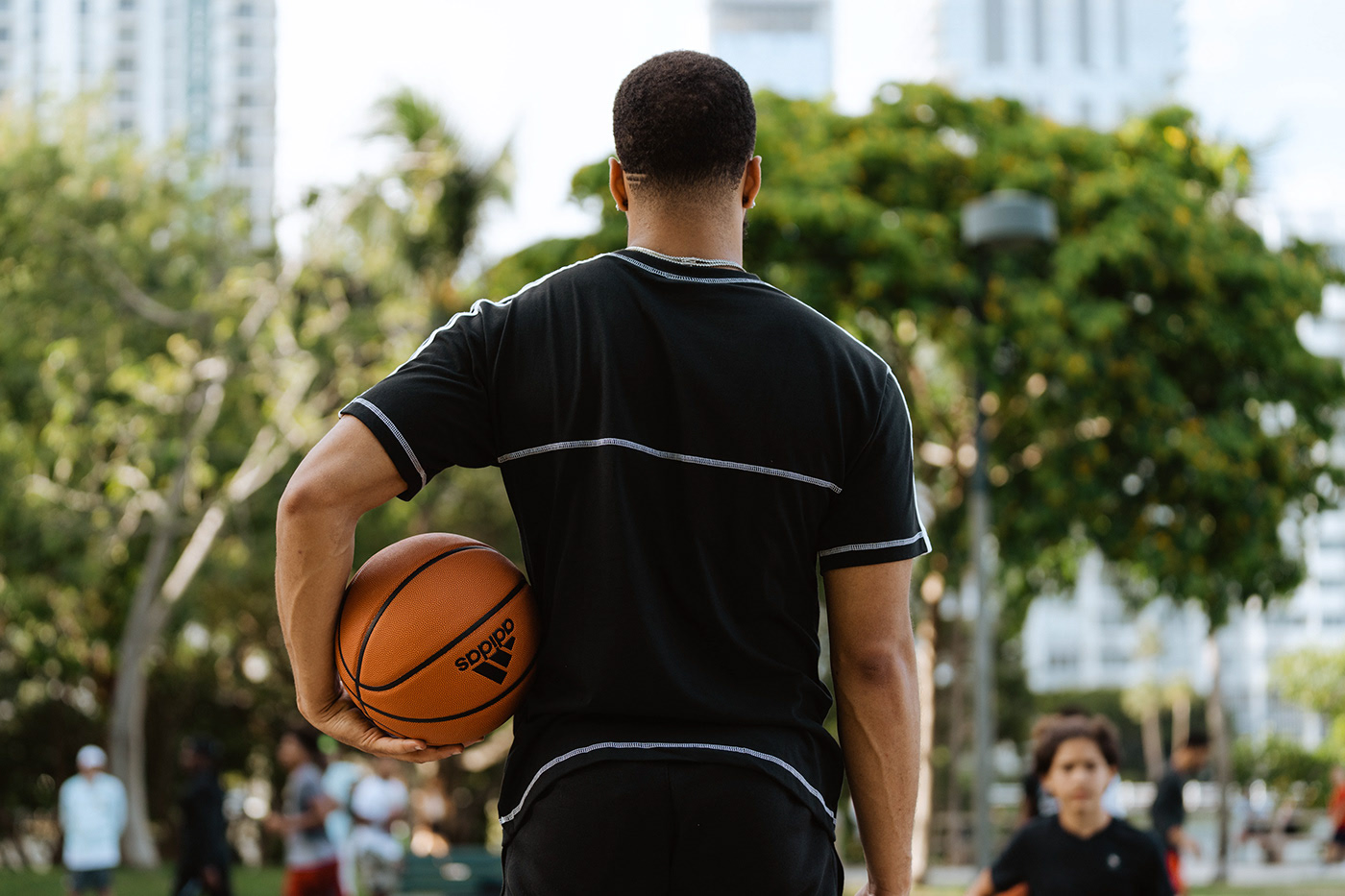 Basketball player holding adidas basketball watching players on a Miami court.