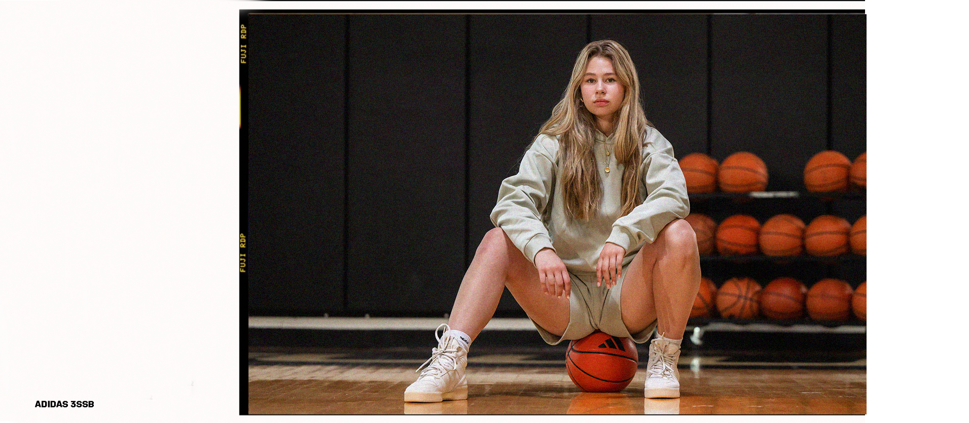 Woman sitting on top of Adidas basketball posing for the brand