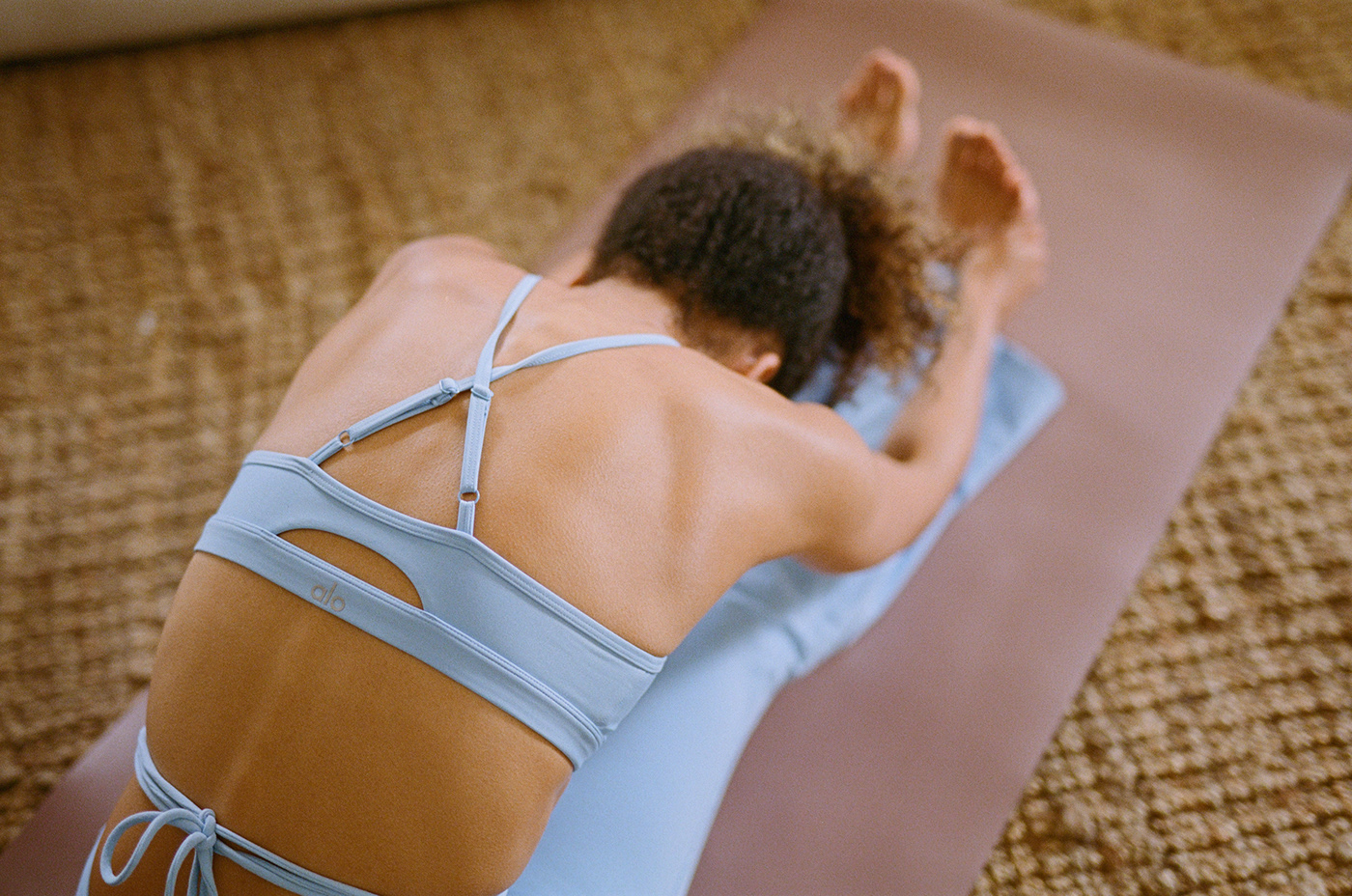 Female model wearing light blue Alo yoga leggings and top as she stretched in the morning on yoga mat